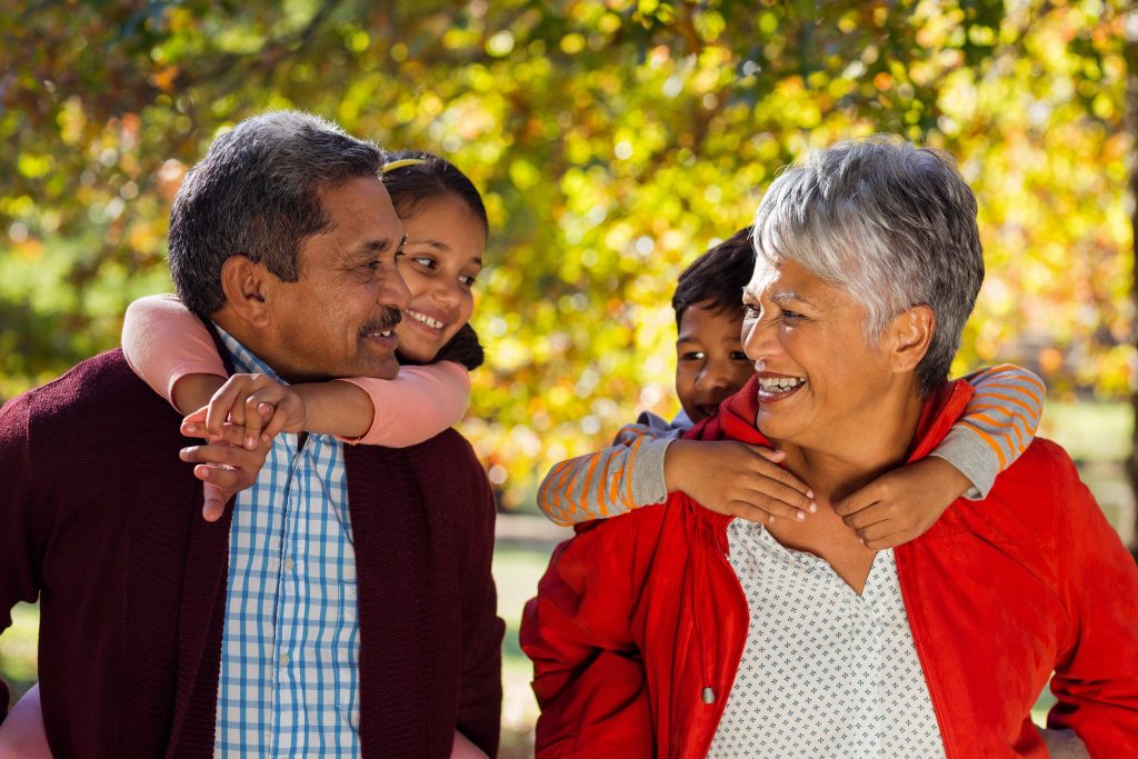 Grandparents piggybacking grandchildren at park